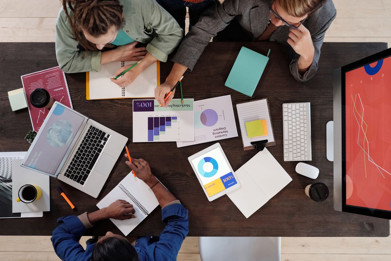 Vue plongeante d’une équipe diversifiée collaborant sur un projet dans un bureau moderne.